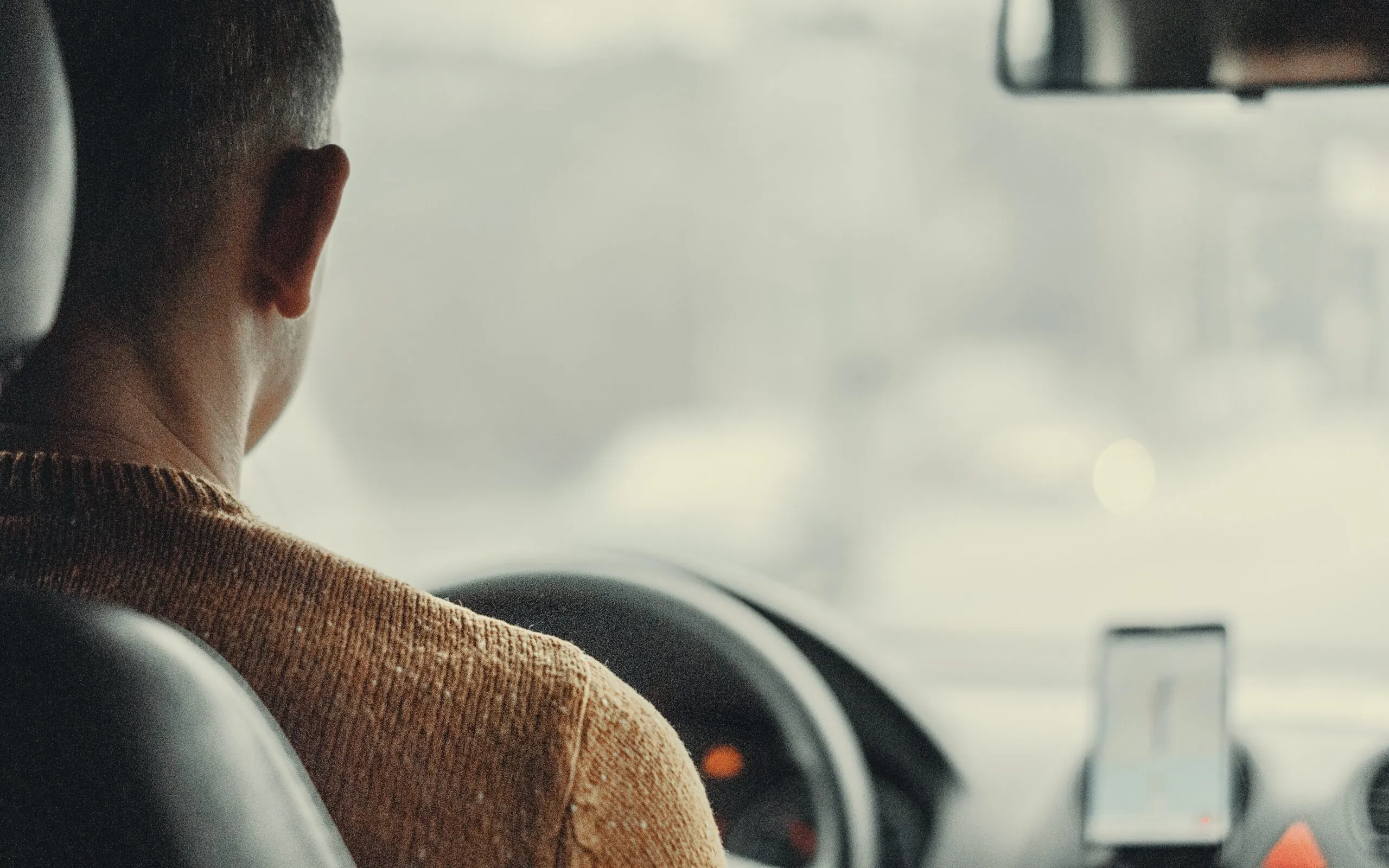 A driver behind the wheel seen from the back seat